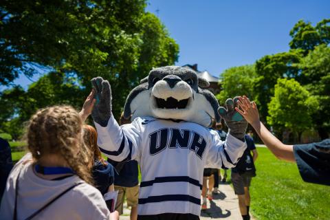 Students high five Wild-E-Cat at Become the Roar, a UNH tradition that happens at New Student Orientation