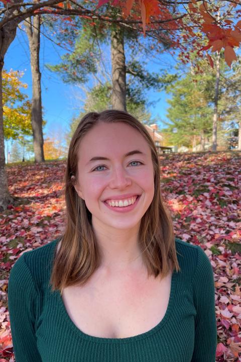 Young woman outside smiling near fall leaves