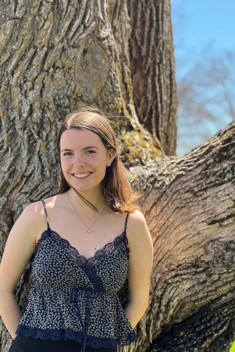 Young woman smiling outside by a tree