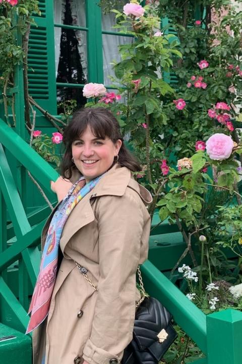 Brunette woman standing on green stairs next to roses