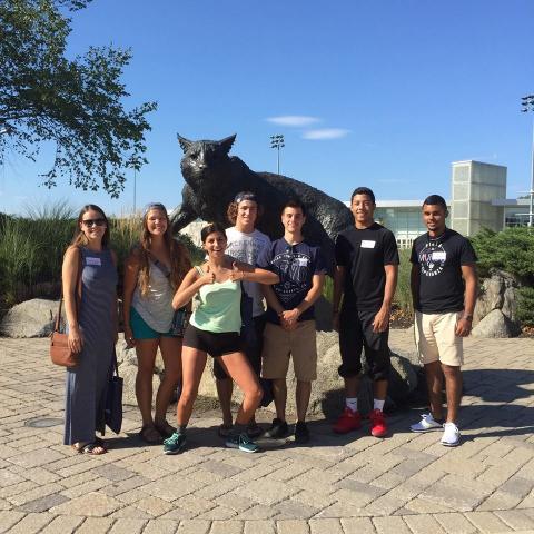 group of UNH students posing with wildcat sculpture