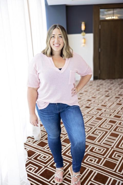 A woman in a pink shirt and jeans with her hand on her him