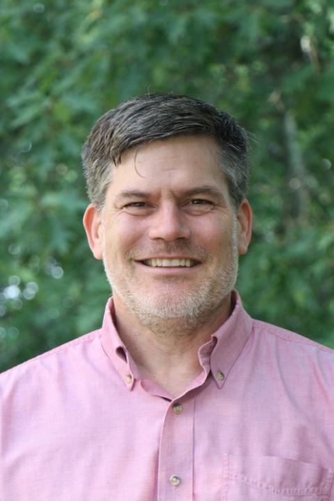 Man in a pink button down shirt smiling
