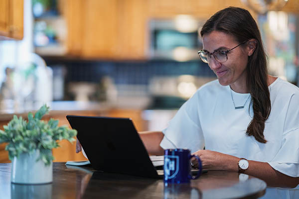 Girl with glasses on a tablet at the kitchen table