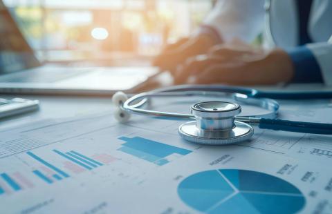 A stethoscope lies on top of a sheet of graphs and charts