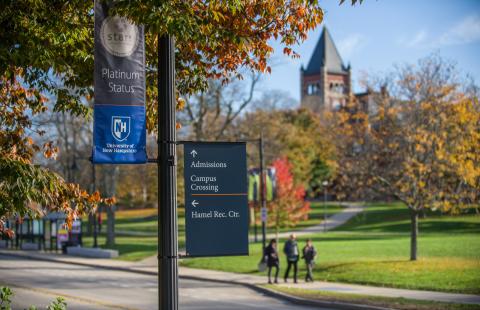 Image of a banner hanging from a light pole in front of Thompson Hall