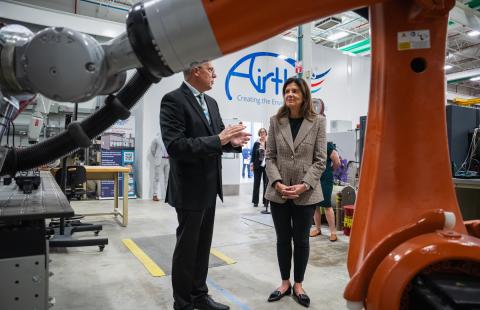 A man and a woman stand beneath a large robot talking
