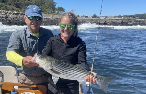 Adrienne Kovach with large striped bass, fisherman Jim Smith 
