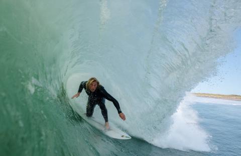 Image from inside a wave of a surfer ducking low on his board
