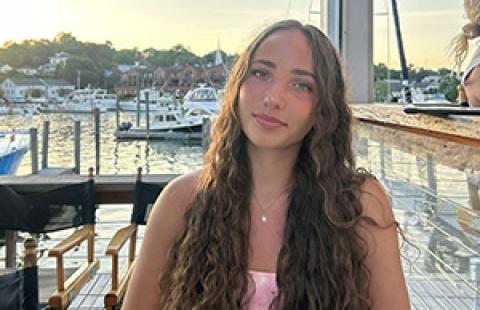 person outside with a dock, boats, and water in the background
