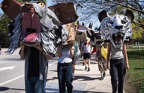 Students wearing large masks walk in a campus parade