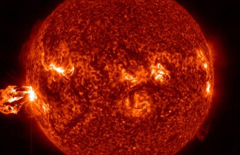 Visualization of the sun's surface with an eruption on the left side.