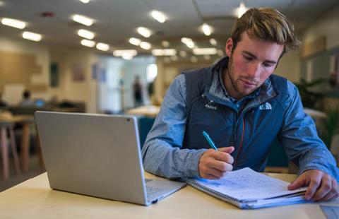 A male student works at a laptop