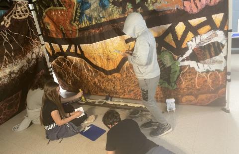 Three middle schoolers work against a backdrop of soils