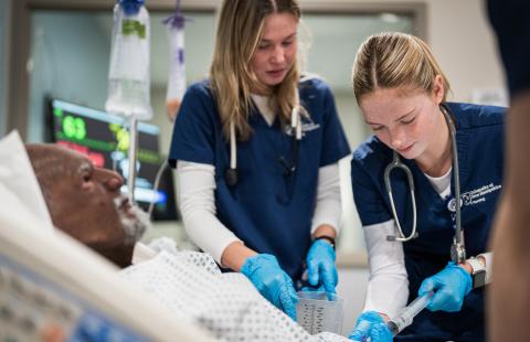Students practice clinical skills on a mannikin at the UNH Health Sciences Simulation Center. 
