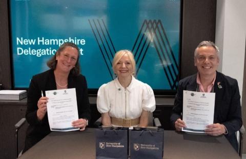 Three people smile at the cameras holding paper at the signing of the agreement between UNH and Space Hub Yorkshire