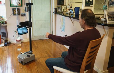 Brian Marquis works out with Robbie, a robot designed at UNH to aid people with Alzheimer’s or other forms of dementia