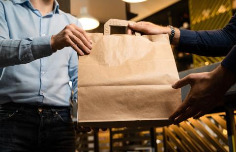 Stock image of a customer receiving a brown paper bag of food.