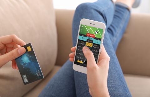 Stock image of a person placing a bet on their phone.