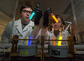 Researchers in lab with glowing test tubes