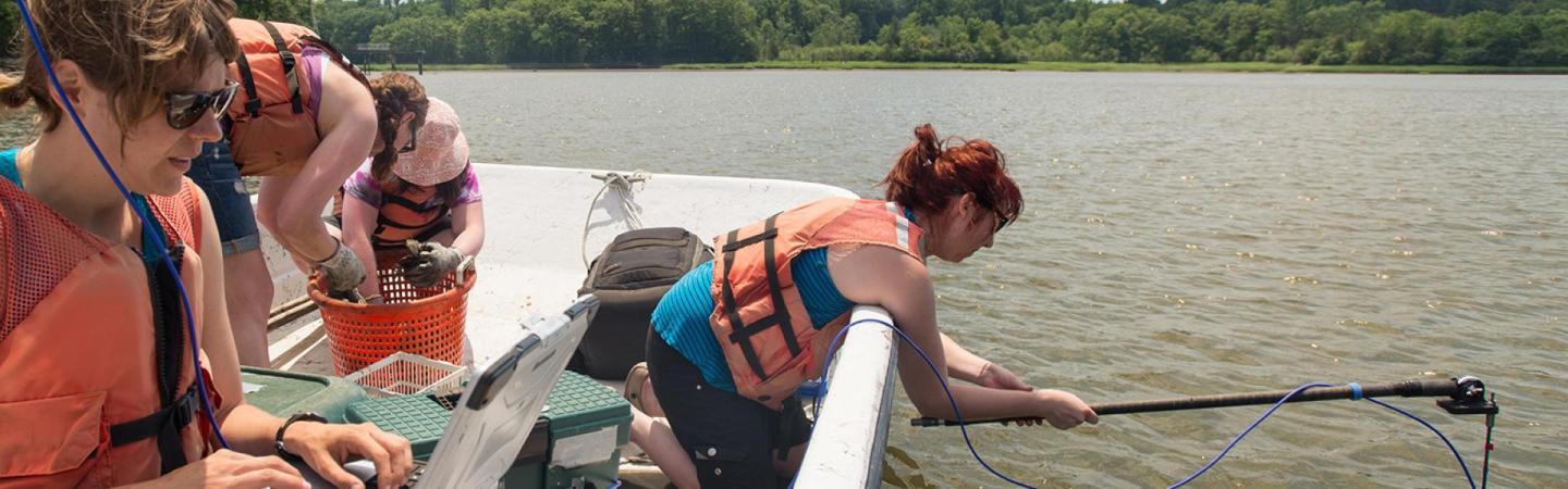 people in boat on lake collecting data for research