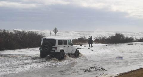 White jeep driving through flood water along coast