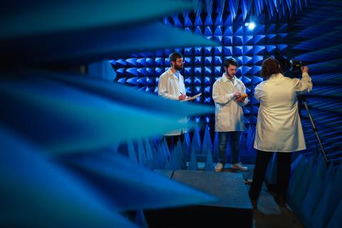 Three researchers stand in anechoic chamber with blue acoustic spikes