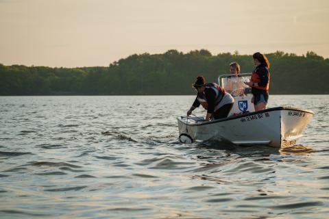 Three researchers are in a small boat at sunrise