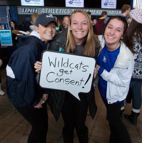 3 students stand with a whiteboard that says Wildcats Get Consent!