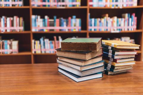 A stack of books on a table in a library
