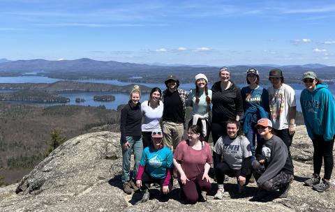 smiling group of students and staff members on the summit of mount major in New Hampshire