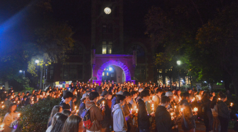 large crowd standing for take back the night event holding candles in front of Thompson Hall