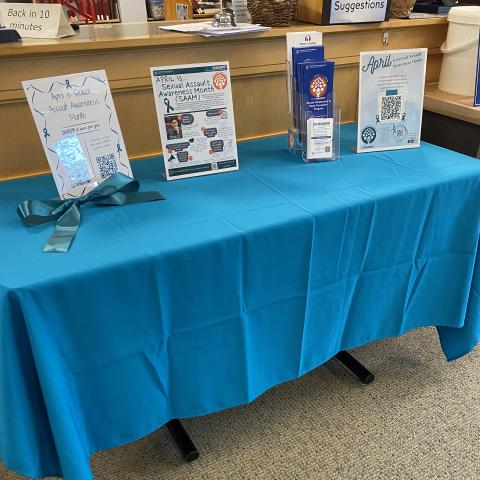 Picture of a SHARPP Center table in the UNH Law library with information and resources relating to Sexual Assault Awareness Month