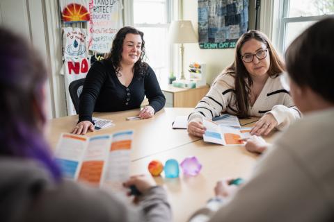 A group of people sitting at a conference room table looking at brochures