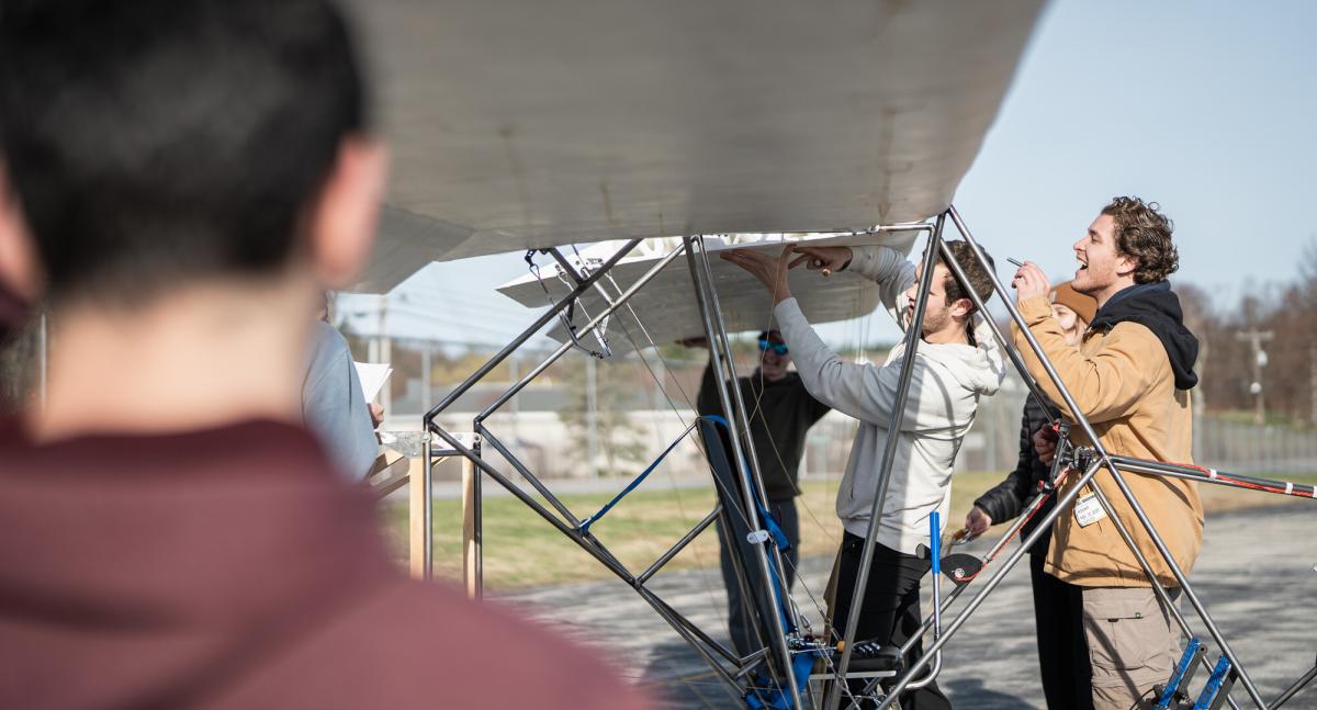 UNH students examining the wings of an aircraft