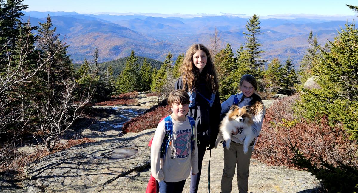 Three young hikers pose on a mountain top