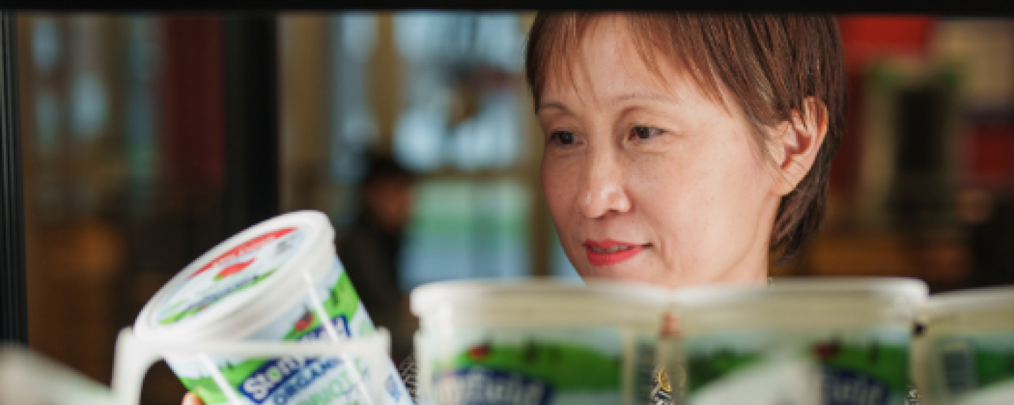 Professor of Marketing Shuili Du examines a container of Stonyfield Farm yogurt, highlighting her research on corporate social responsibility initiatives of yogurt brands.