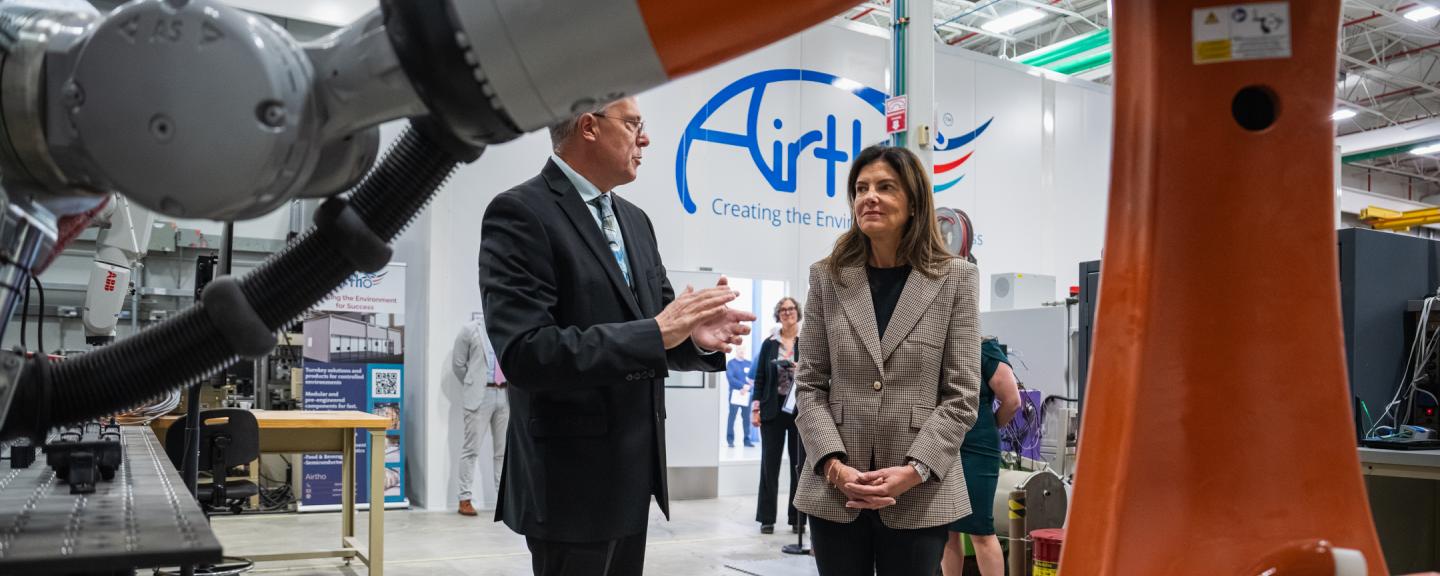A man and a woman stand beneath a large robot talking