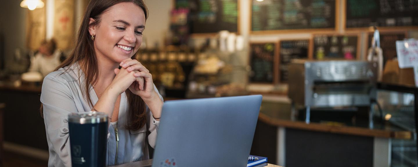 A woman looks at a computer on a table in a coffee shop