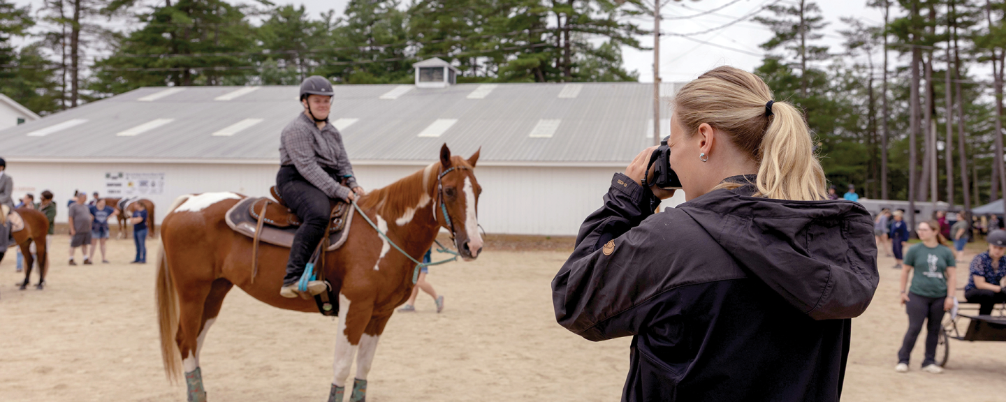 A woman takes a photo of an equestrian competition
