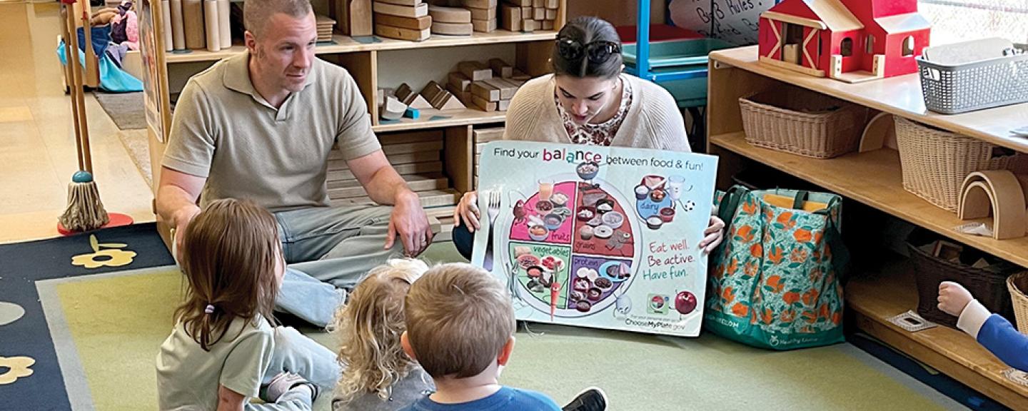 Two adults read a story to a group of pre-schoolers