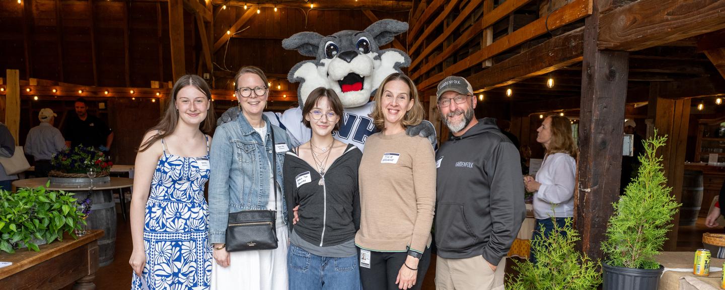 Five guests pose with Wild E Cat mascot in a barn