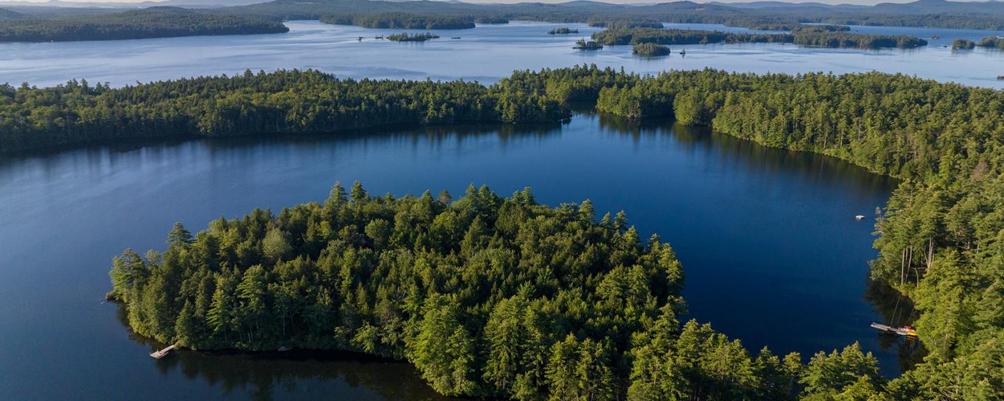 Aerial view of a blue lake with pine tree-covered islands