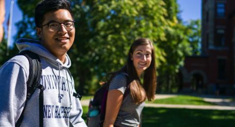 Three students walking and smiling on UNH campus