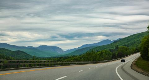 car driving on empty highway with mountains in backgroun
