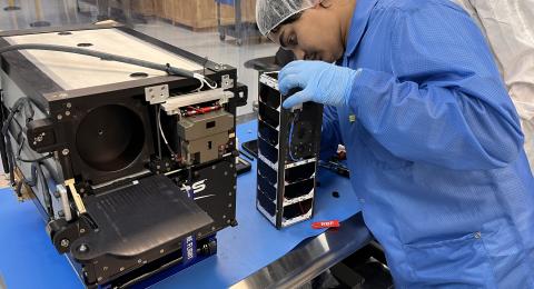Sanjeev Mehta, a UNH research project engineer for the 3UCubed mission, inspects the CubeSat