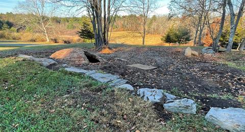 A stone foundation and brick structure are visible in a yard