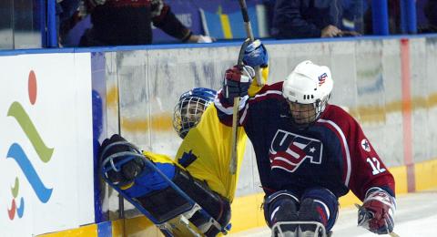 Hockey player checking another player into a wall