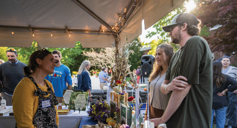 Group of students talking at a booth with fresh fruits and vegetables