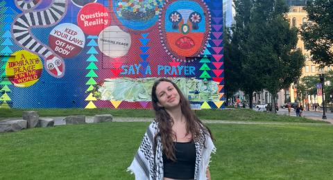 person standing outside on a lawn with a colorful mural in the background